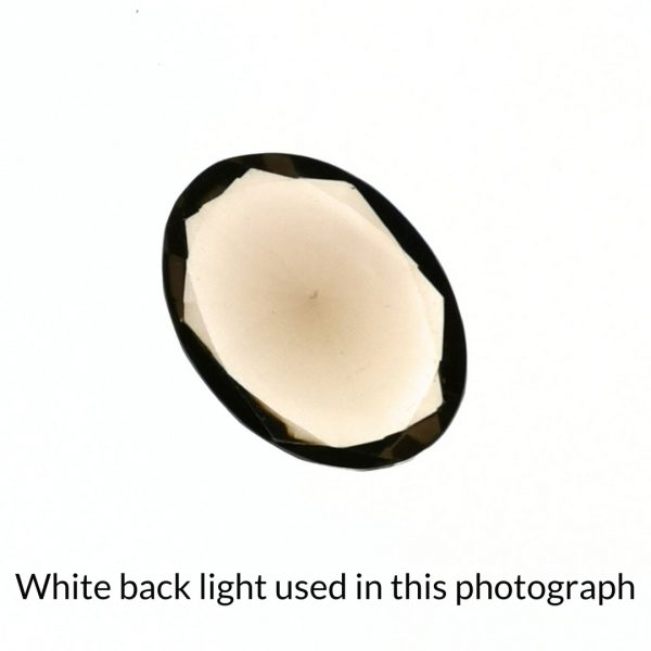 The brown smoky quartz oval gem is being back-lit with a bright white light to show any inclusions within the gem more clearly.