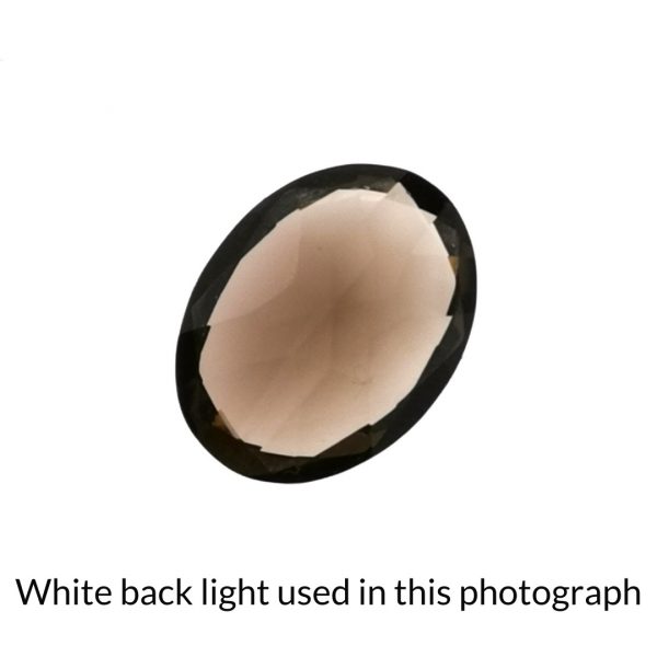 The brown smoky quartz oval gem is being back-lit with a bright white light to show any inclusions within the gem more clearly.