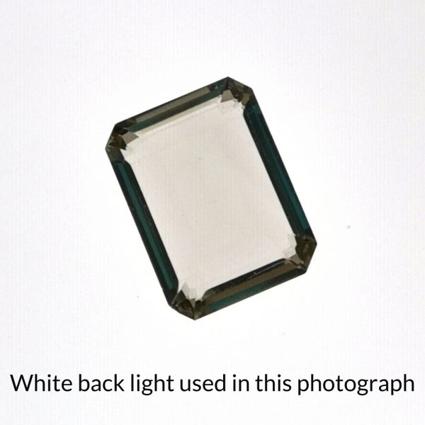 The smoky quartz gem is being back-lit with a bright white light to show any inclusions within the gem more clearly.
