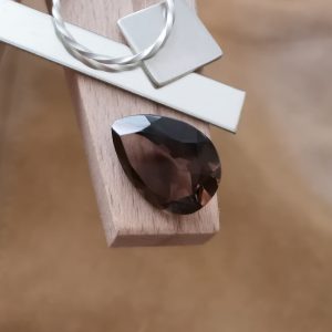 The brown smoky quartz teardrop displayed on a jewellers bench peg with some sterling silver sheet and wire.