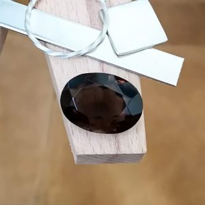 The brown smoky quartz oval displayed on a jewellers bench peg with some sterling silver sheet and wire.