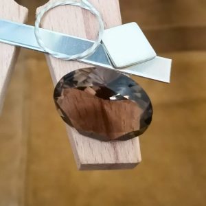 The brown smoky quartz oval displayed on a jewellers bench peg with some sterling silver sheet and wire.