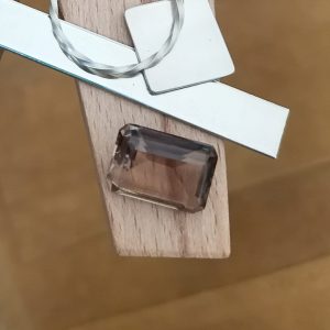 The brown smoky quartz rectangle displayed on a jewellers bench peg with some sterling silver sheet and wire.