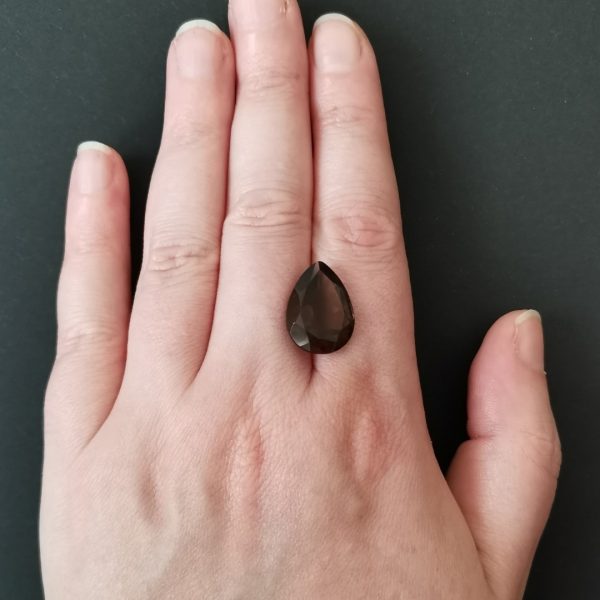 The brown smoky quartz gemstone resting on a hand to give an idea of the gemstone size and colour.