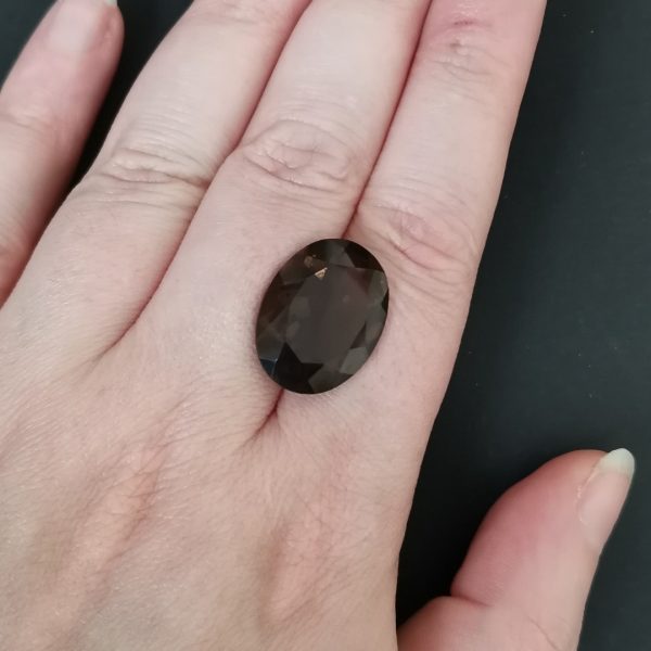 The brown smoky quartz gemstone resting on a hand to give an idea of the gemstones size and colour.