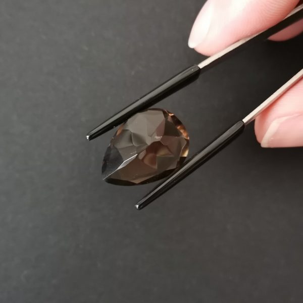 a photo of the pavilion of the brown smoky quartz teardrop against a black background