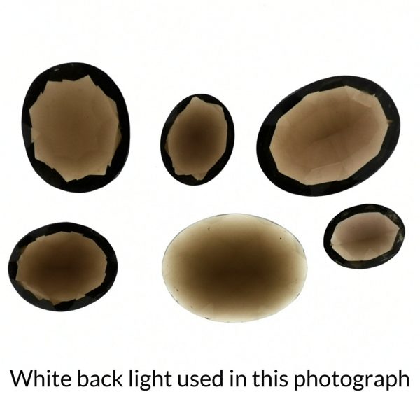 The smoky quartz oval gems are being back-lit with a bright white light to show any inclusions within the gem more clearly.