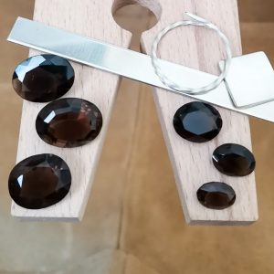 This bundle of 6 smoky quartz ovals are displayed on a jewellers bench peg with some sterling silver sheet and wire.