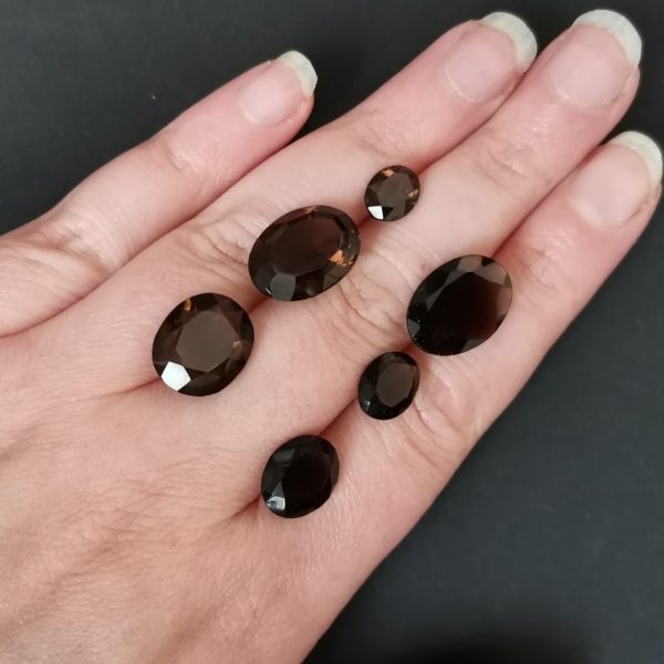The dark brown smoky quartz gemstones resting on a hand to give an idea of the gemstones size and colour.