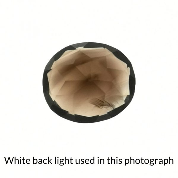 The brown smoky quartz oval gem is being back-lit with a bright white light to show any inclusions within the gem more clearly.