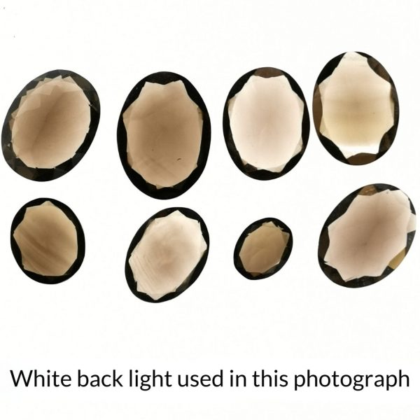 The brown smoky quartz oval gems are being back-lit with a bright white light to show any inclusions within the gem more clearly.