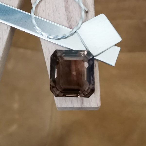 The brown smoky quartz square displayed on a jewellers bench peg with some sterling silver sheet and wire.