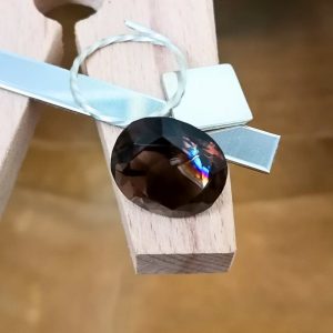 The smoky quartz oval displayed on a jewellers bench peg with some sterling silver sheet and wire.
