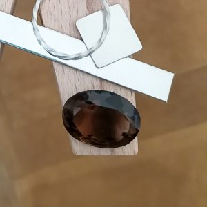 The rich brown smoky quartz oval displayed on a jewellers bench peg with some sterling silver sheet and wire.