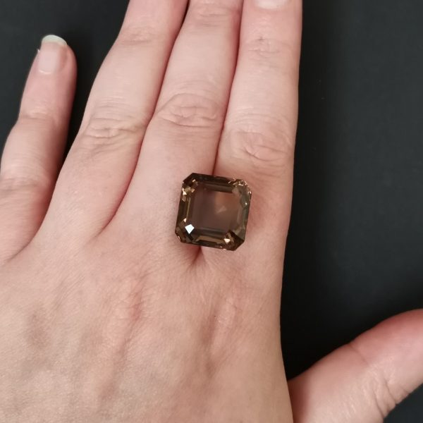 The brown smoky quartz gemstone resting on a hand to give an idea of the gemstone size and colour.