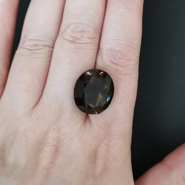 The brown smoky quartz gemstone resting on a hand to give an idea of the gemstones size and colour.