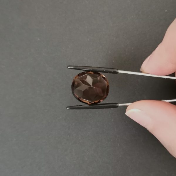 a photo of the pavilion of the brown smoky quartz oval against a black background