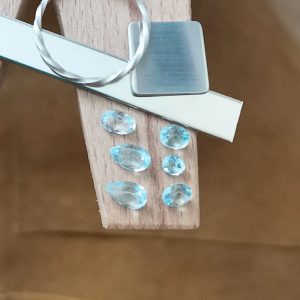 The sky blue topaz bundle displayed on a jewellers bench peg with some sterling silver sheet and wire.