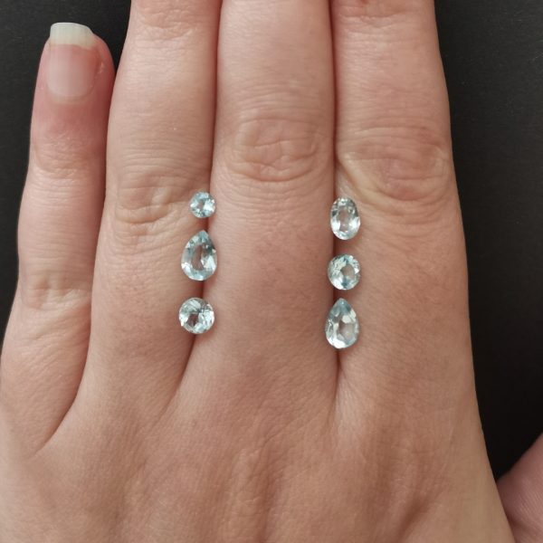 The blue topaz gemstones resting on a hand to give an idea of the gemstone size and colour.