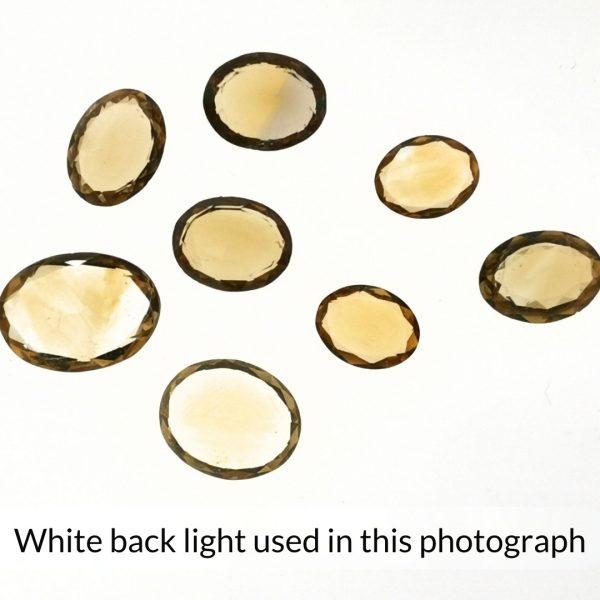 The golden citrine oval gems is being back-lit with a bright white light to show any inclusions within the gems more clearly.