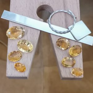 The bundle of golden yellow citrine ovals displayed on a jewellers bench peg with some sterling silver sheet and wire.