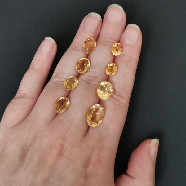 The golden yellow citrine gemstones resting on a hand to give an idea of the gemstone size and colour.