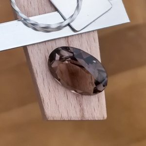 The brown smoky quartz oval displayed on a jewellers bench peg with some sterling silver sheet and wire.