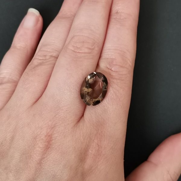 The brown smoky quartz gemstone resting on a hand to give an idea of the gemstone size and colour.