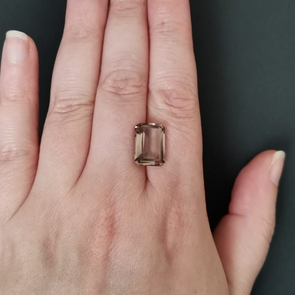 The brown smoky quartz gemstone resting on a hand to give an idea of the gemstone size and colour.