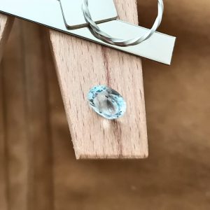The blue aquamarine oval displayed on a jewellers bench peg with some sterling silver sheet and wire.