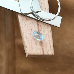 The blue aquamarine oval displayed on a jewellers bench peg with some sterling silver sheet and wire.