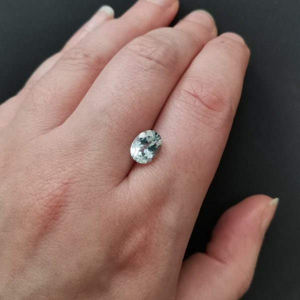 The pale blue aquamarine gemstone resting on a hand to give an idea of the gemstones size and colour.