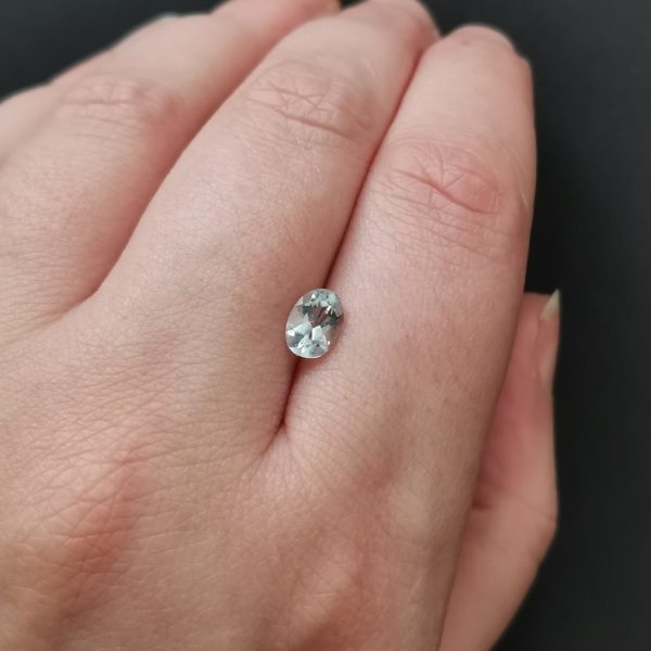 The pale blue aquamarine gemstone resting on a hand to give an idea of the gemstones size and colour.