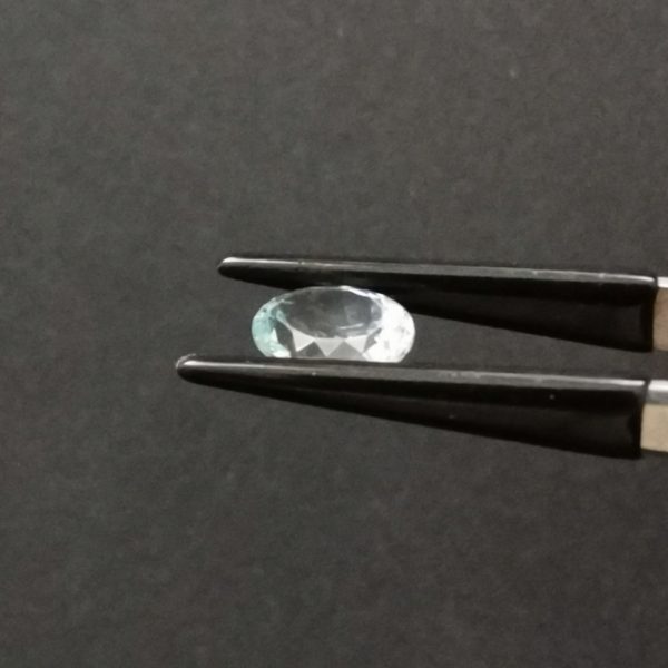 A photo of the top of the pale blue aquamarine showing the scratch on the table of the gem.