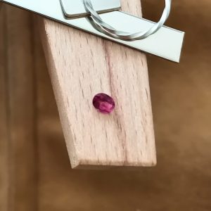 The pink garnet oval displayed on a jewellers bench peg with some sterling silver sheet and wire.