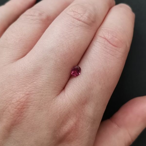 The pink garnet gemstone resting on a hand to give an idea of the gemstones size and colour.