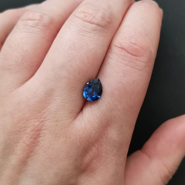 The lab grown blue sapphire gemstone resting on a hand to give an idea of the gemstones size and colour.