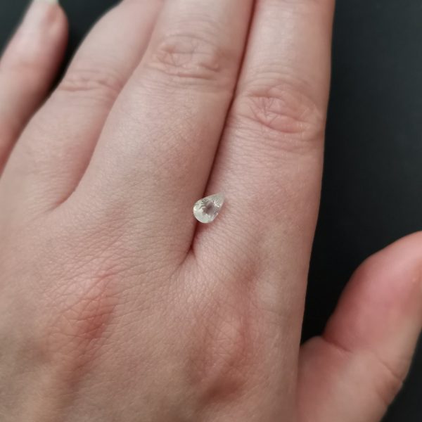The small white moonstone gemstone resting on a hand to give an idea of the gemstones size and colour.