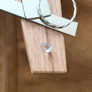 The white moonstone teardrop displayed on a jewellers bench peg with some sterling silver sheet and wire.