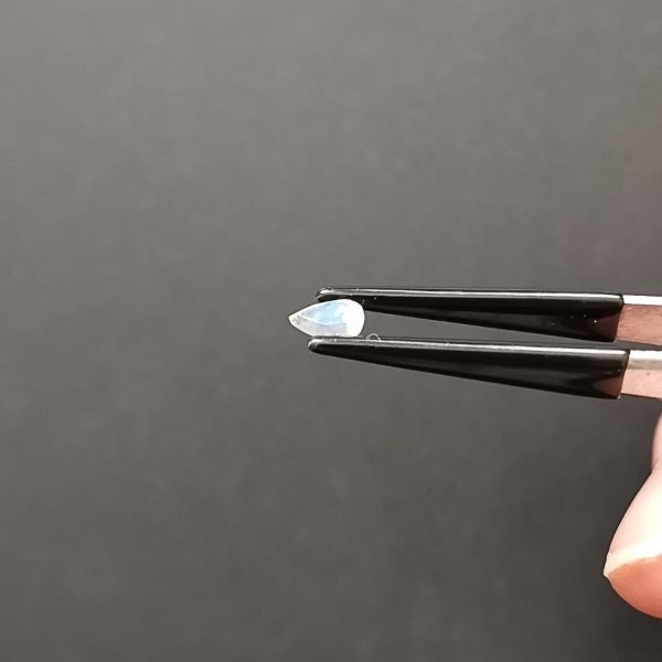 A photo of the white moonstone held at an angle to show the blue shimmer across the moonstones surface.