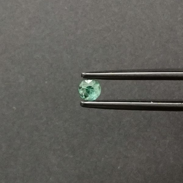 A photo of the crown area of the blueish green tourmaline against a black background