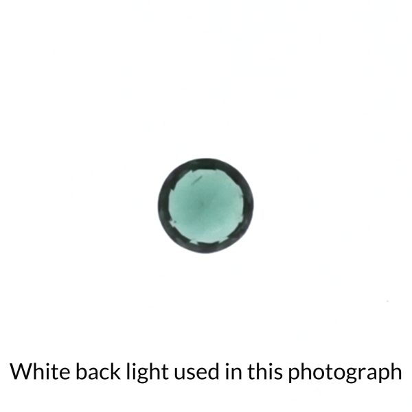 The round tourmaline gem is being back-lit with a bright white light to show any inclusions within the gem more clearly.