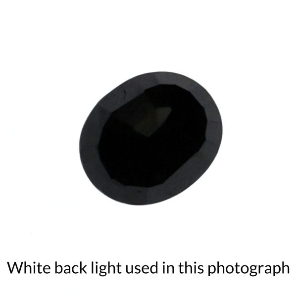 The black sapphire oval gem is being back-lit with a bright white light to show any inclusions within the gem more clearly.