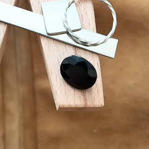 The black sapphire oval displayed on a jewellers bench peg with some sterling silver sheet and wire.