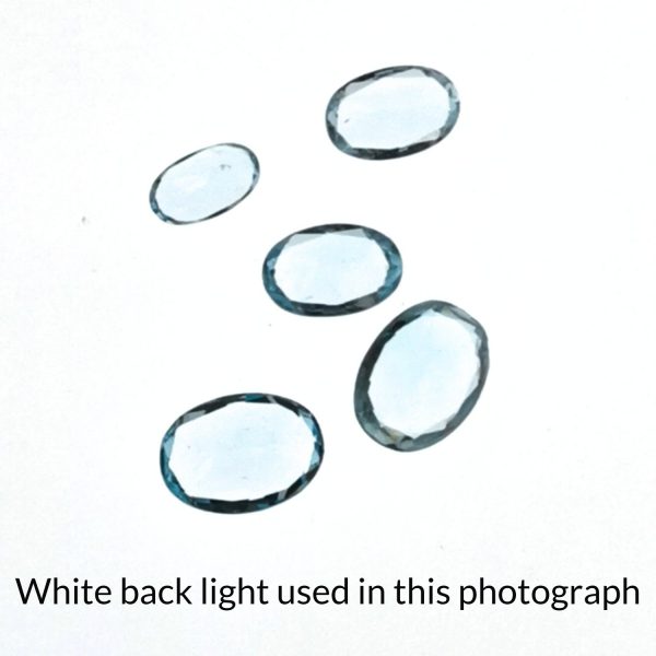 The sky blue topaz oval gems are being back-lit with a bright white light to show any inclusions within the gems more clearly.