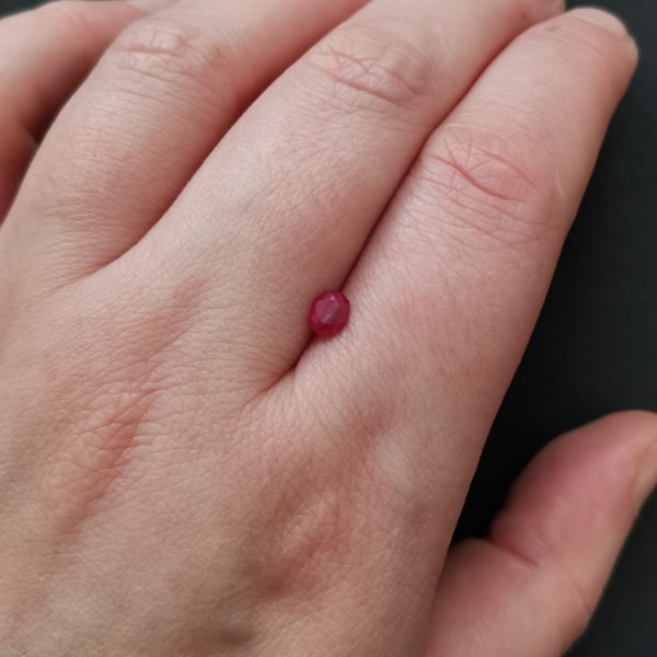 The small ruby gemstone resting on a hand to give an idea of the gemstones size and colour.