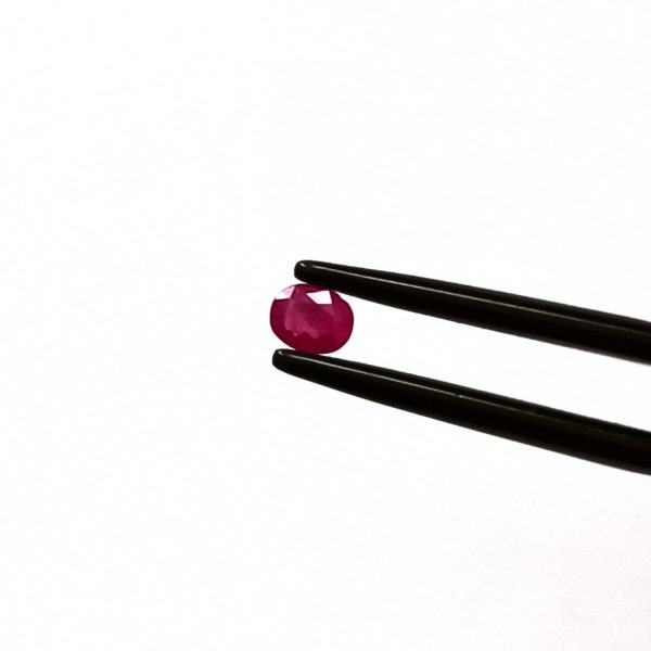 A photo of the crown area of the pinkish red ruby against a white background
