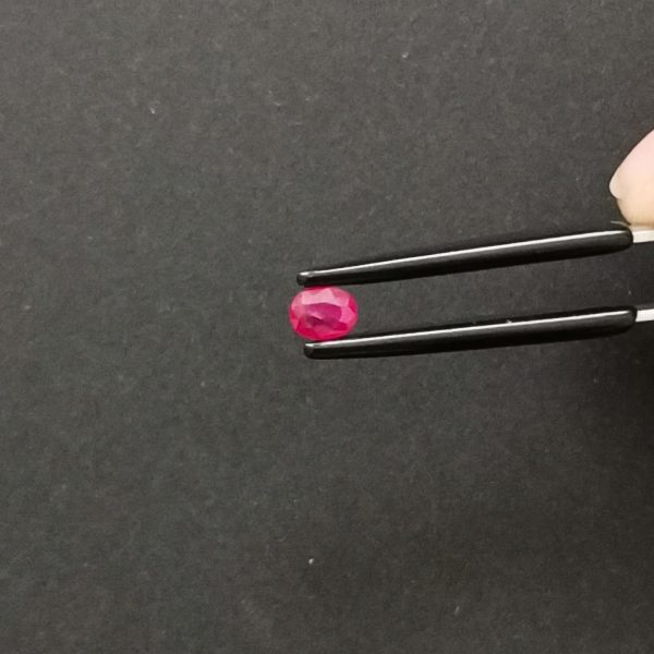 A photo of the crown area of the pinkish red ruby against a black background