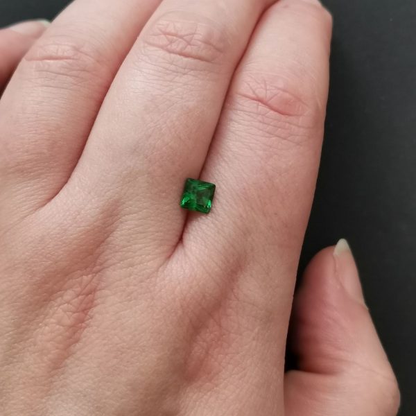The tsavorite garnet gemstone resting on a hand to give an idea of the gemstones size and colour.