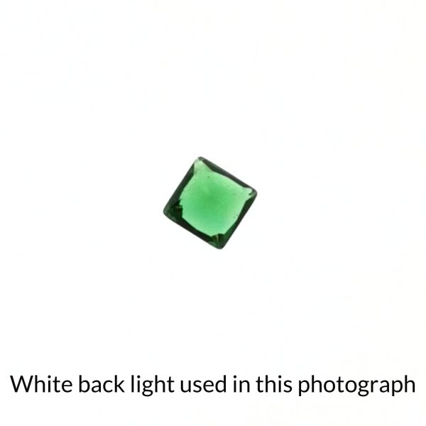 The square green garnet gem is being back-lit with a bright white light to show any inclusions within the gem more clearly.